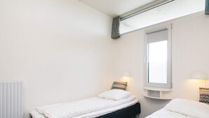 A small, clean room with two single beds, a window, and a radiator. - 4 Person Holiday Park Home in Blokhus (Blokhus)