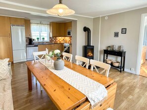 A modern kitchen with a central island, a dining area with a wooden table and chairs, and a built-in wood-burning stove. - 4 Star Holiday Home in Kopingsvik (Kopingsvik)