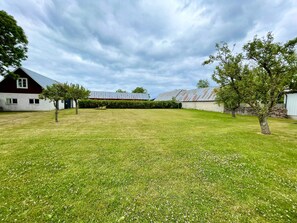 A grassy yard with a red barn, a white building, and a metal structure in the background. - 4 Star Holiday Home in Kopingsvik (Kopingsvik)