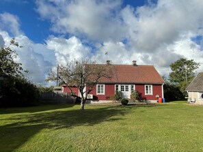 A red house with a tiled roof, surrounded by a well-maintained lawn and a few trees. - 4 Star Holiday Home in Kopingsvik (Kopingsvik)