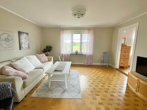 A living room with a sofa, coffee table, and a TV stand. - 4 Star Holiday Home in Kopingsvik (Kopingsvik)