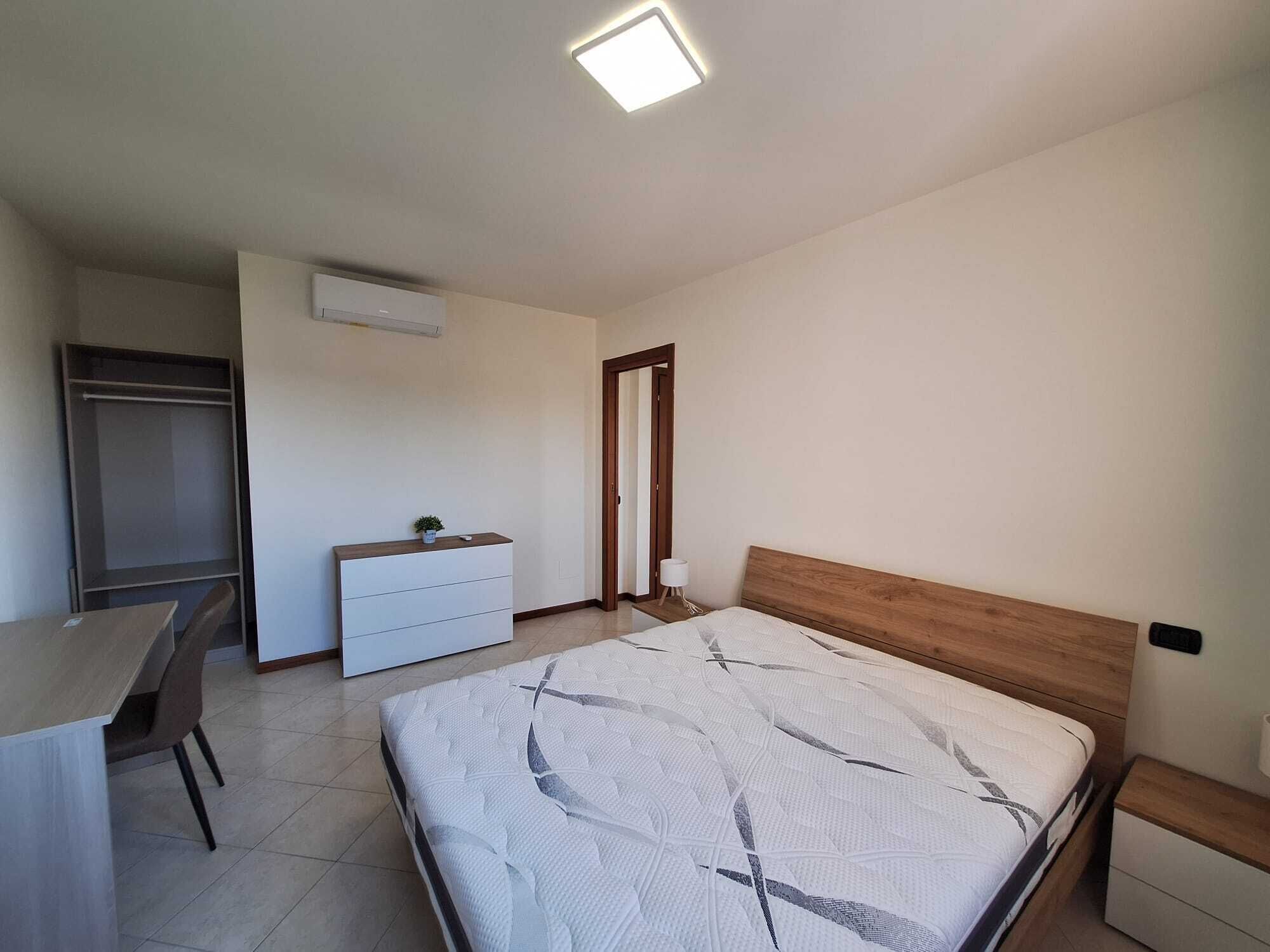 Un dormitorio con cama, escritorio, cómoda y armario.
