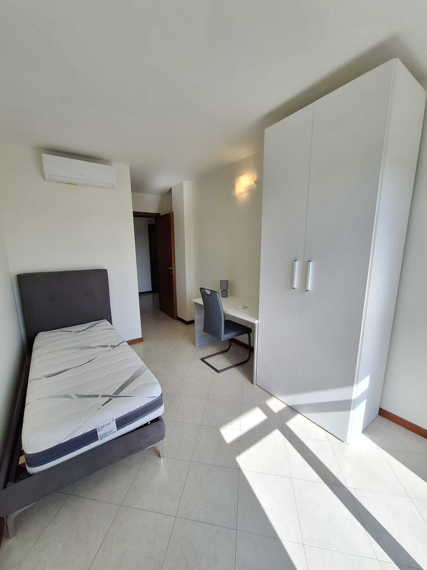 Un dormitorio con cama, escritorio y armario.
