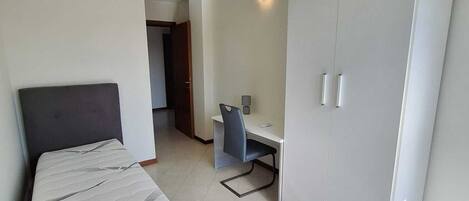 Un dormitorio con cama, escritorio y armario.
