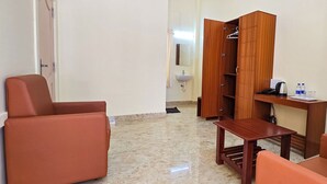 A hotel room with a wooden wardrobe, a small table, a chair, and a sink in the background. - Luna Castle (Palayankottai)