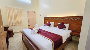 A hotel room with a large bed, a wooden headboard, and a window with curtains.