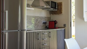 Una cocina compacta con un refrigerador de acero inoxidable, un microondas y una cafetera sobre la encimera.