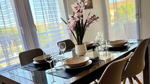 A dining table set with plates, glasses, and a vase of flowers.
