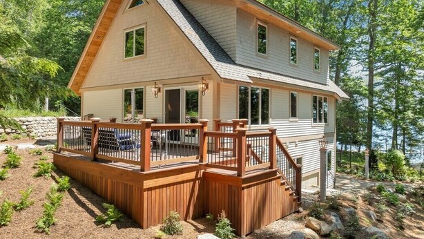 Ein zweistöckiges Haus mit einer Holzterrasse und einer Steinmauer.