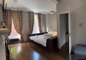 A bedroom with a large bed, a radiator, a window with curtains, and a door leading to another room. - Covent Garden House, 4-bed, Sleeps 10 (London)