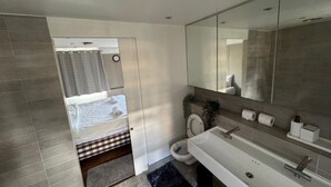 A modern bathroom with a large mirror, a toilet, and a sink.