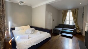 A modern hotel room with a large bed, a sofa, and a small table.