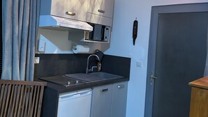 A compact kitchen with a built-in oven, a sink, and a door with a screen.