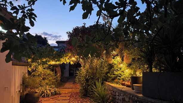 A pathway leading through a garden with stone walls and potted plants.