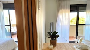 Une chambre d’hôtel avec un lit, une table à manger dressée avec des assiettes, des verres et une plante.