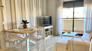 Un salon moderne comprenant un coin repas, un téléviseur et un canapé.
