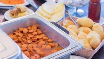 Un buffet proposant divers plats, notamment des saucisses en tranches, des petits pains et un récipient de soupe.