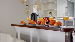 Aamiaispöytä, jossa on tarjolla croissantteja, hedelmiä ja appelsiinimehua puupöydällä.
