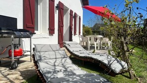 A patio with two sun loungers, a red gas cylinder, and a white table with chairs. - Serenity and relaxation 3 km from the beach (Tarnos)