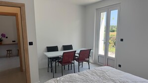 A bedroom with a bed, a dining table with chairs, and a sliding glass door leading to a balcony. - Serenity and relaxation 3 km from the beach (Tarnos)