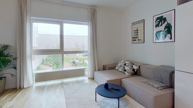 A modern living room with a large window, a sofa, a coffee table, and two framed pictures on the wall. - 2 Person Holiday Park Home in Testby (Malmö)