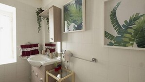 A bathroom with a white sink, a mirror, a towel rack with a red towel, and two framed leaf paintings on the wall. - Room Giulia By Dimorra (Napoli)