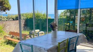 A conservatory with a table set for two, large glass windows, and a view of the sea.