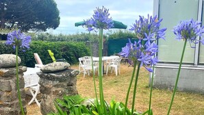 A garden with a table and chairs, a stone wall, and a building in the background.
