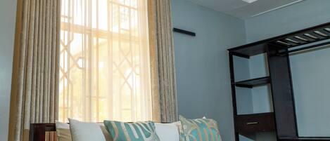 Una habitación de hotel con cama, cortinas, ventana y armario.