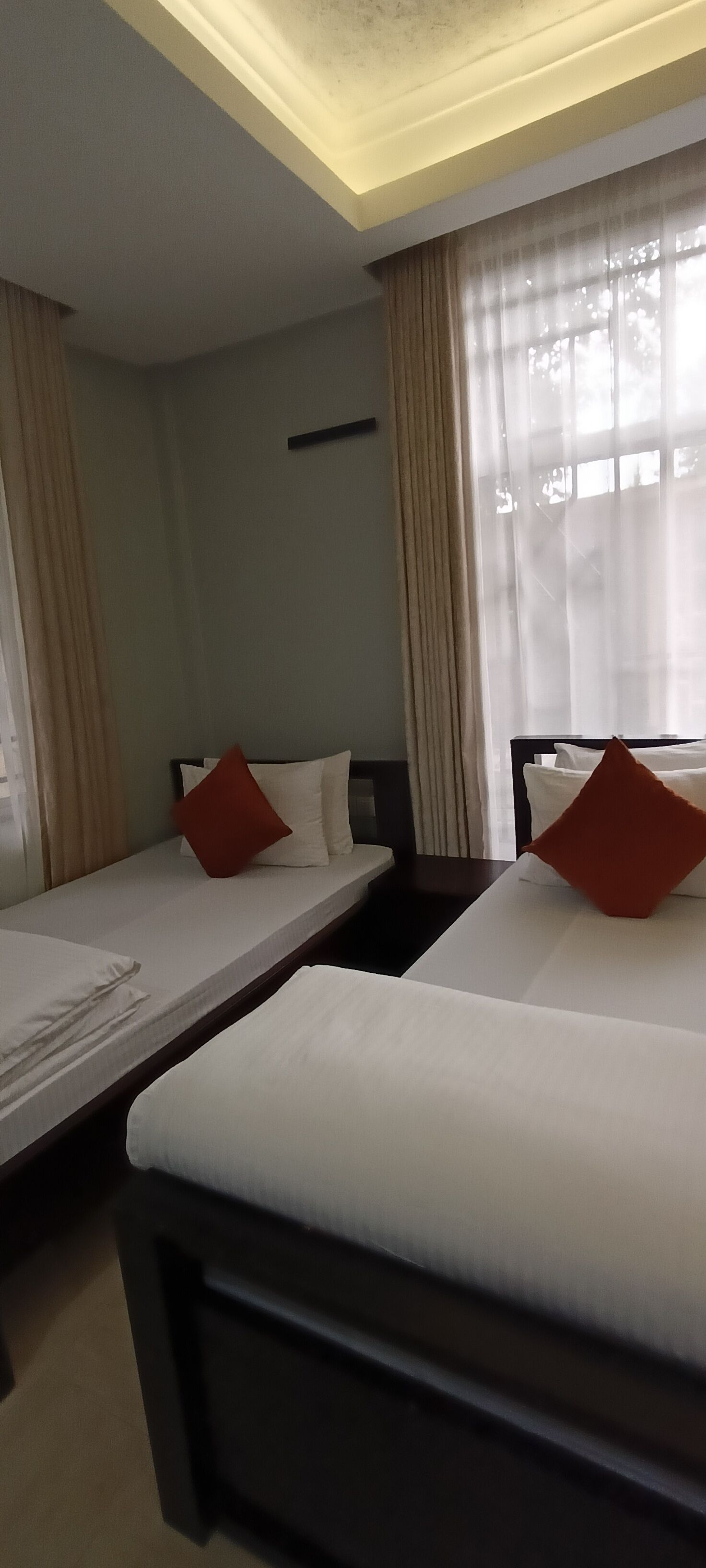Una habitación de hotel con dos camas individuales, cada una con una almohada y una manta.