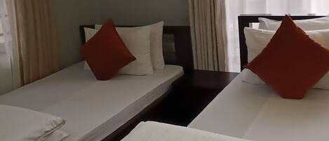 Una habitación de hotel con dos camas individuales, cada una con una almohada y una manta.