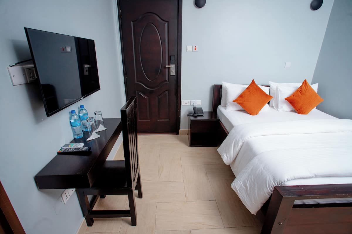 Ein Hotelzimmer mit Bett, Schreibtisch, Fernseher und Tür.