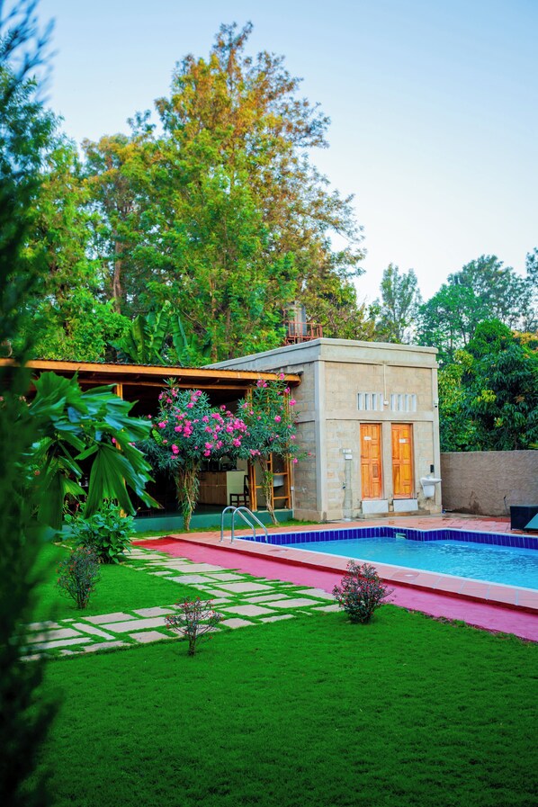 Une maison moderne dotée d’une piscine, entourée d’une végétation luxuriante et d’une pelouse bien entretenue.