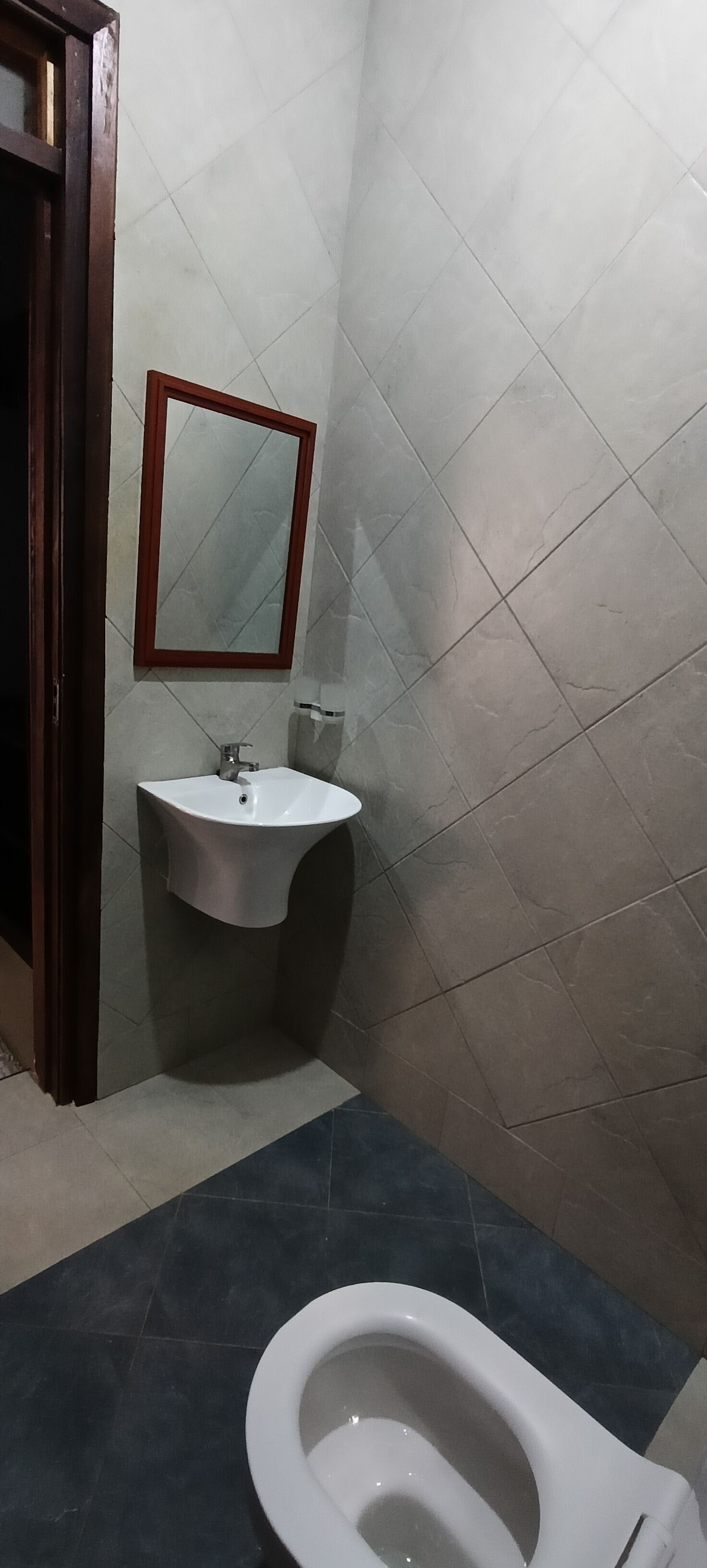 Un baño con lavamanos blanco, espejo e inodoro.