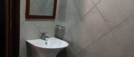 Un baño con lavamanos blanco, espejo e inodoro.