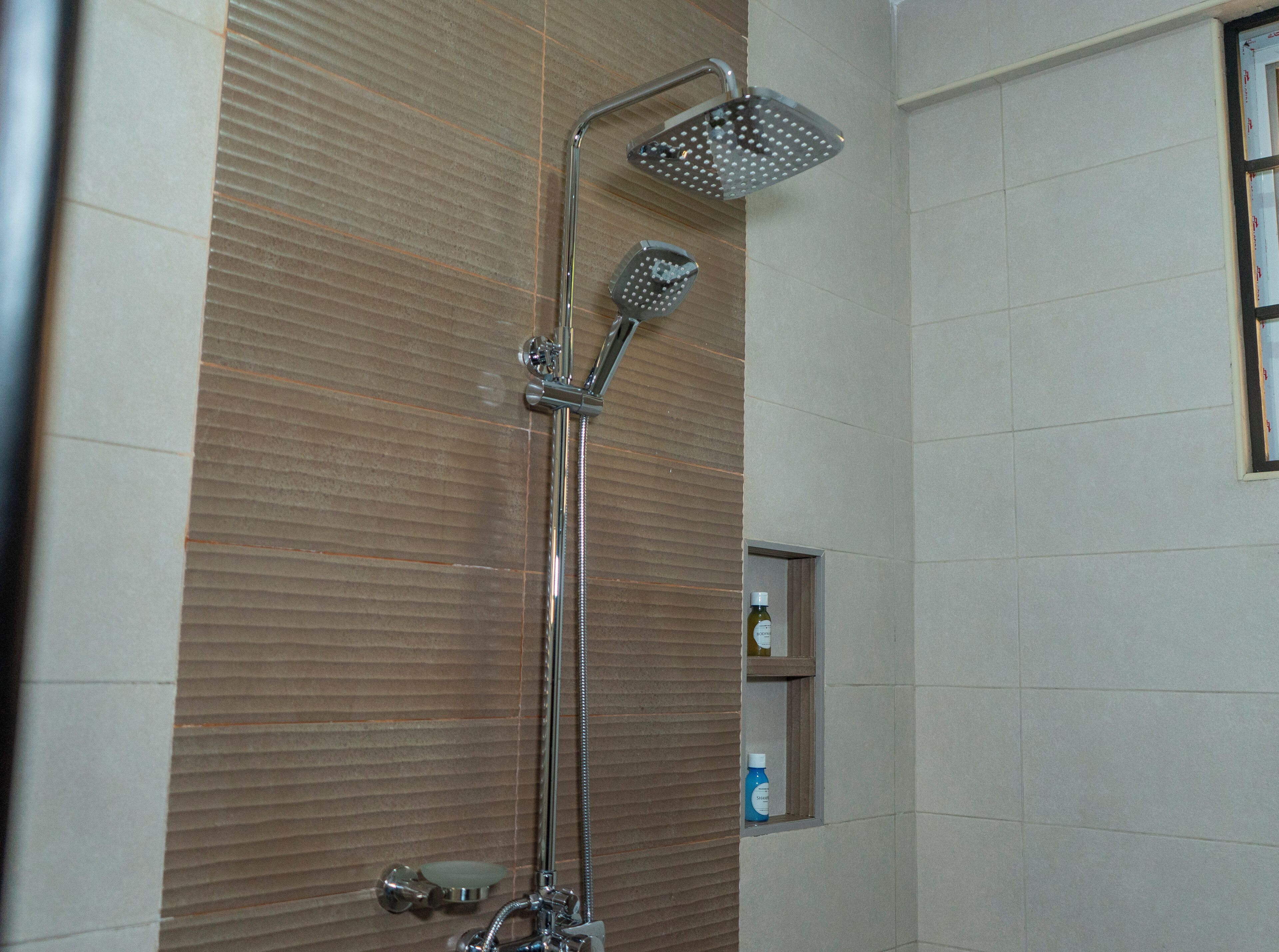 A shower with a handheld showerhead and a wall-mounted rainhead.