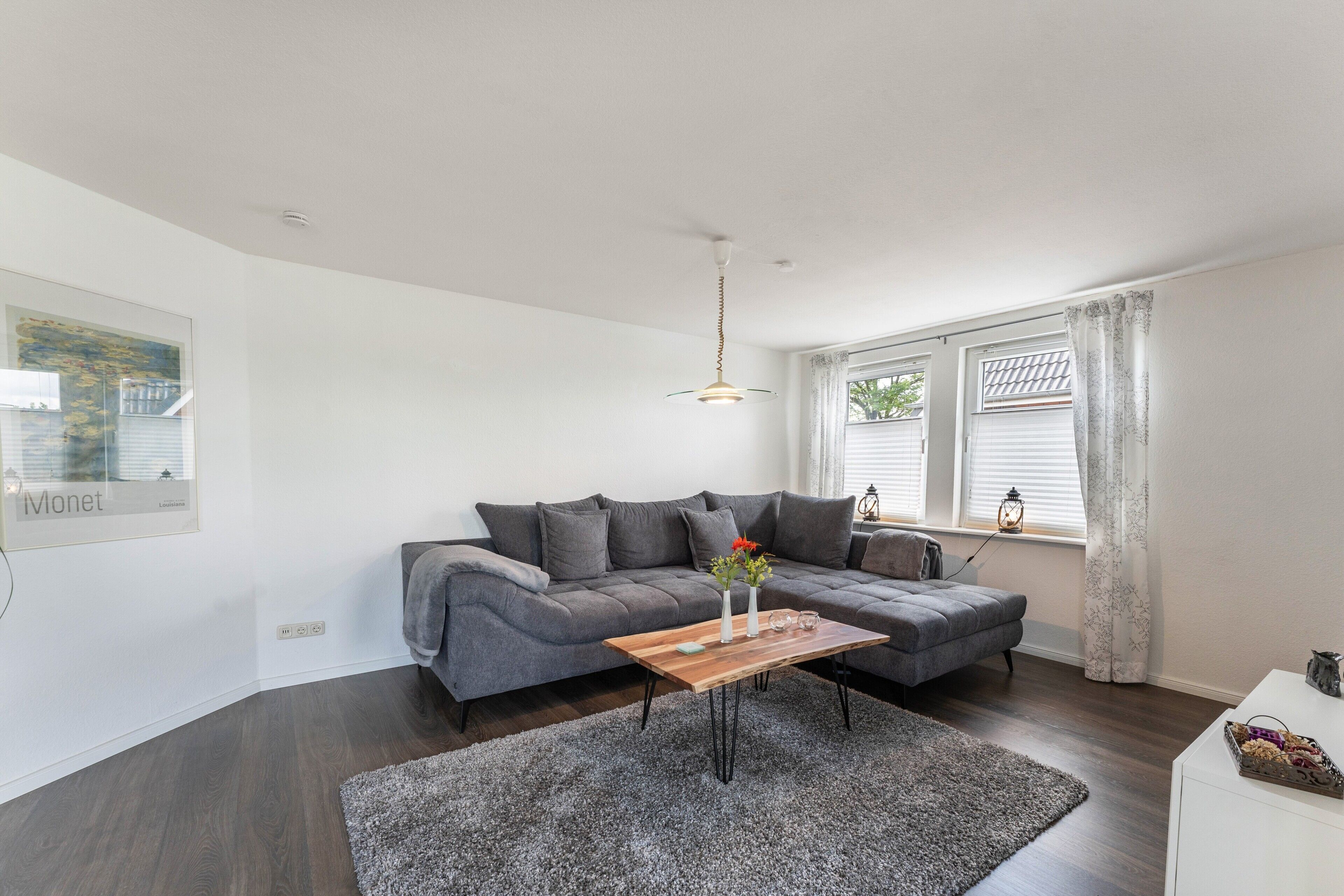Una sala de estar moderna con un sofá seccional gris, una mesa de centro de madera y una alfombra gris.