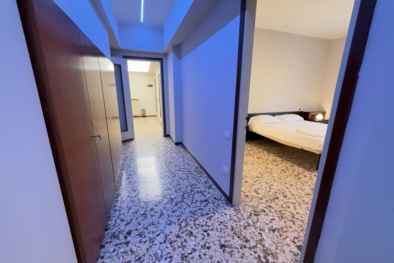 A hotel hallway with a bed, a wardrobe, and a fire extinguisher.
