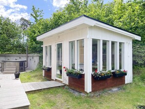 A small, white, single-story structure with large windows and wooden deck access. - 4 Person Holiday Home in Vaxholm (Vaxholm)