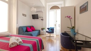 A modern hotel room with a bed, a sofa, a desk, and a TV. - At Giulia's Home Vomero Apt (NAPOLI)
