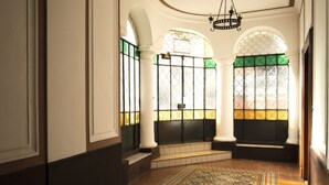 A hallway with a patterned carpet, a chandelier, and a set of double doors with stained glass windows. - At Giulia's Home Vomero Apt (NAPOLI)