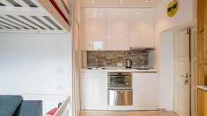 A compact kitchen with white cabinets, a built-in oven, and a coffee maker.