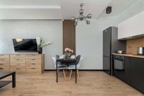 A modern kitchen with a dining table, chairs, a TV, and a built-in oven.