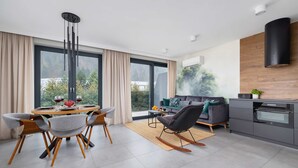 A modern living space with a dining area, a sofa, and a kitchen. - Spacious Apartment | Balcony | Parking | Mountain View (Szczyrk)