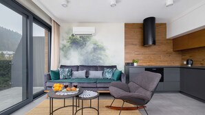 A modern living room with a sofa, a rocking chair, a coffee table, and a view of the outdoors. - Spacious Apartment | Balcony | Parking | Mountain View (Szczyrk)