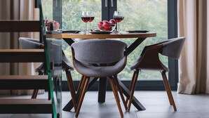 A dining area with a table set for two, a modern chandelier, and a view of greenery outside. - Spacious Apartment | Balcony | Parking | Mountain View (Szczyrk)