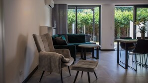 A modern living room with a sofa, armchair, ottoman, and dining table.