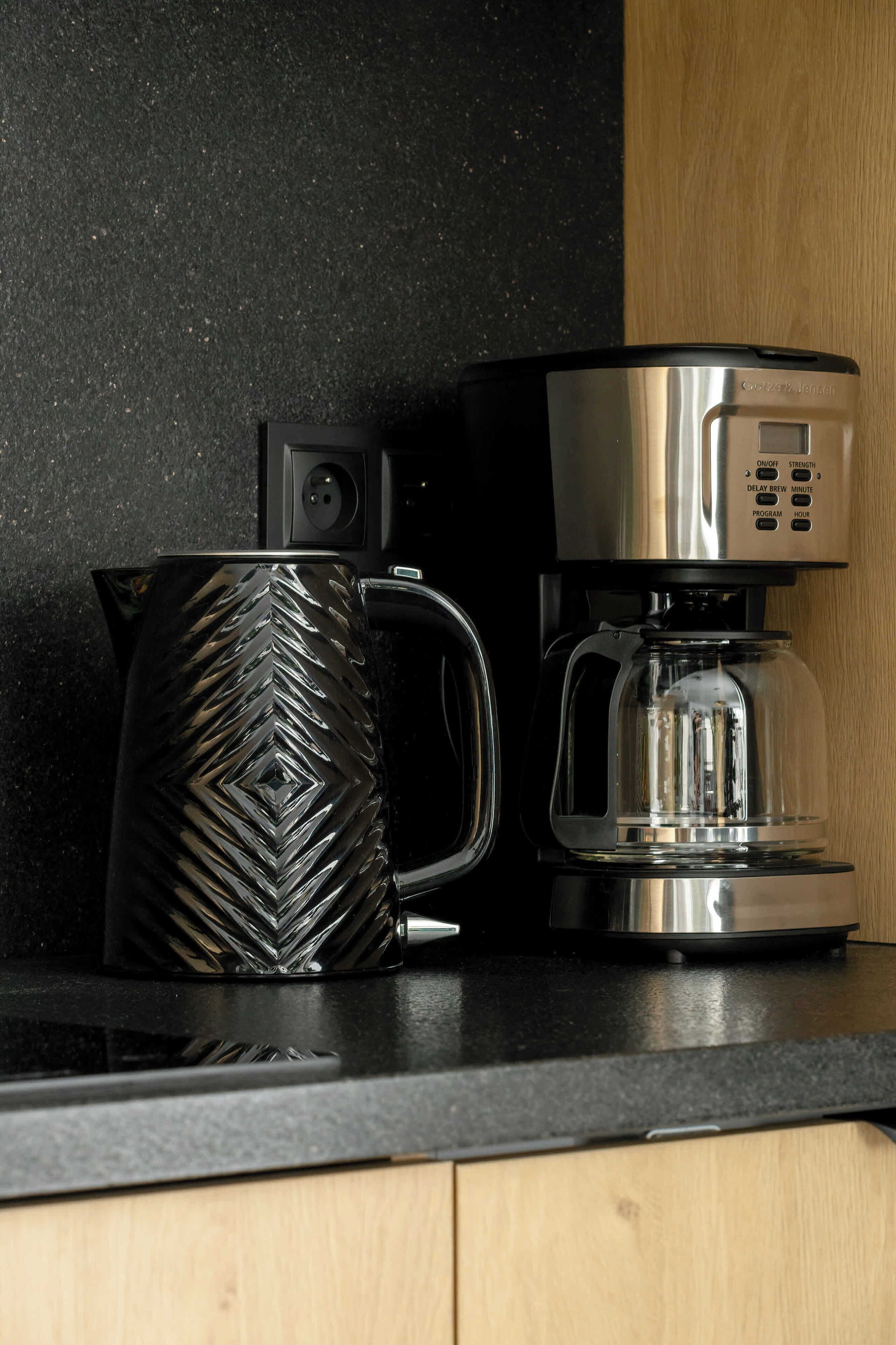 A coffee maker and a black mug on a kitchen counter.