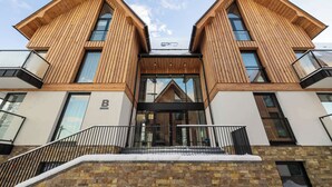 Un edificio moderno con facciata in legno simmetrica, ampie finestre e un ingresso centrale con porta in vetro.