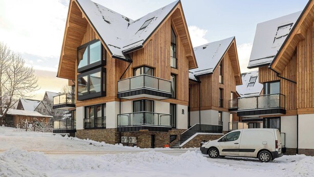 Un edificio moderno a più piani con pareti esterne in legno, ampie finestre e balconi.